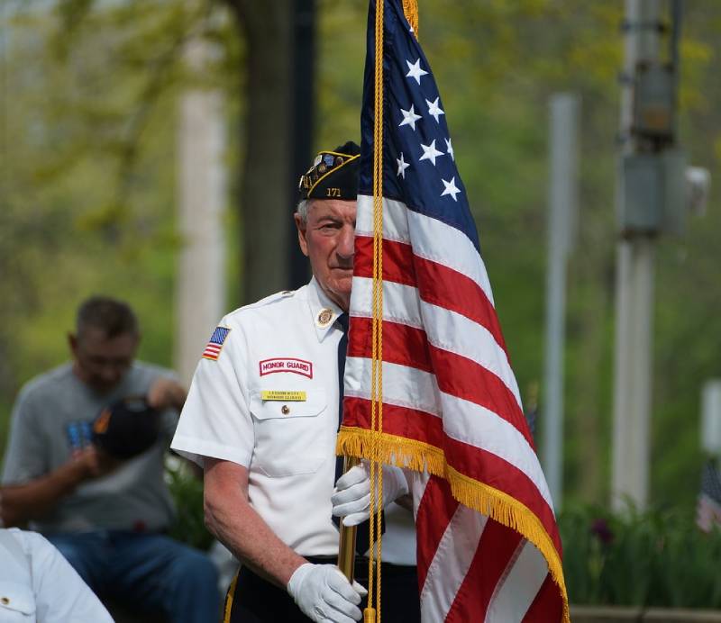 A man in uniform holding an american flag.